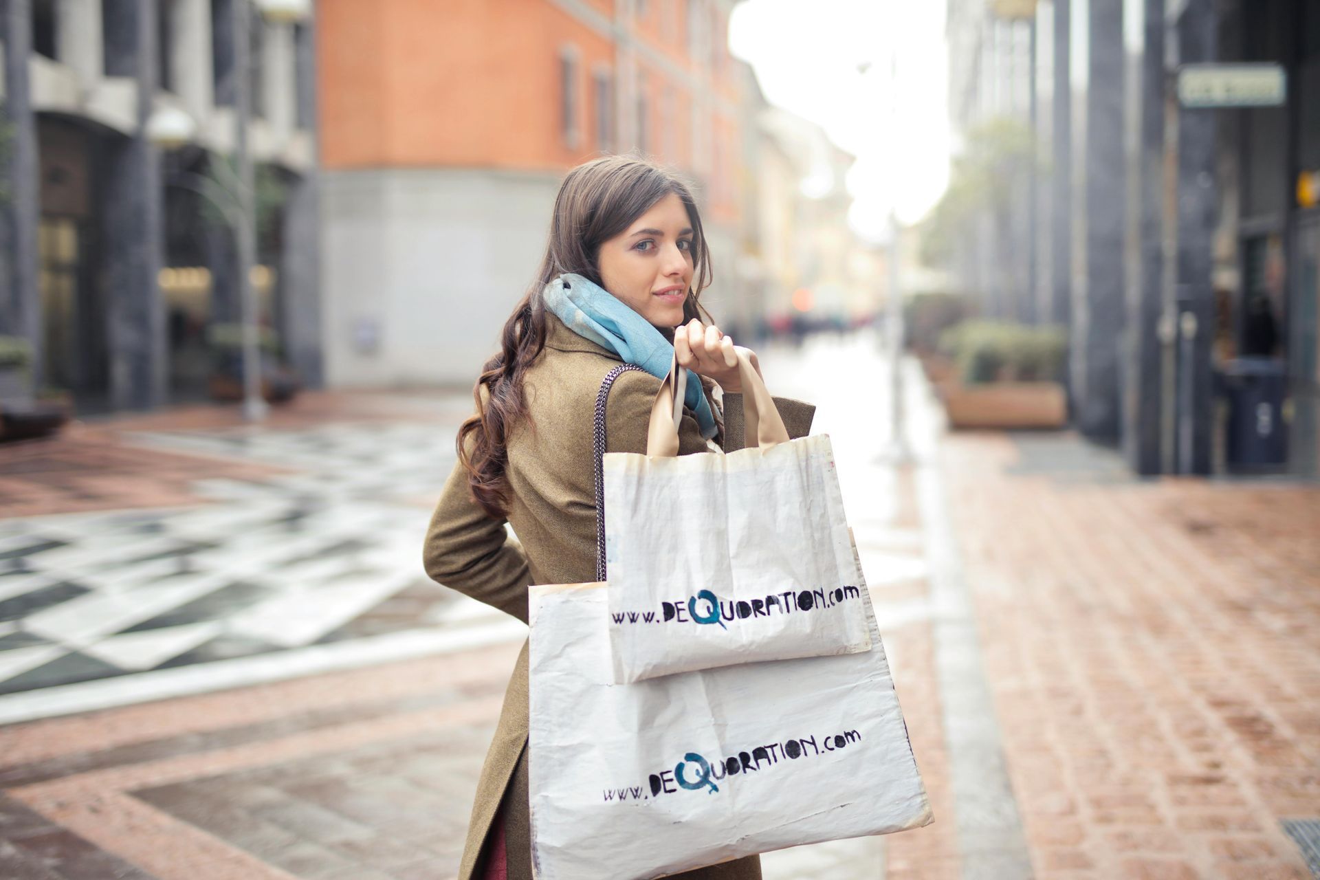 A woman is walking down the street with shopping bags and talking on a cell phone.
