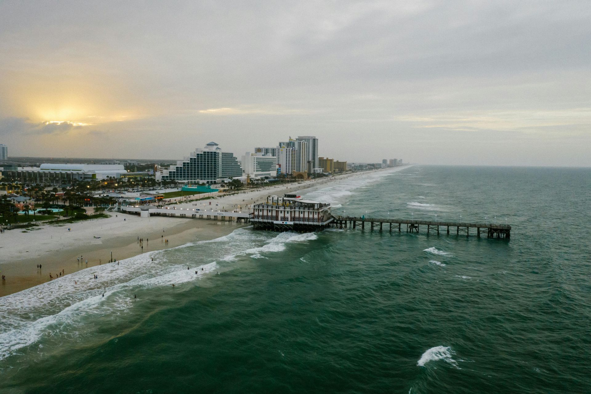 An aerial view of a pier on a beach at sunset.