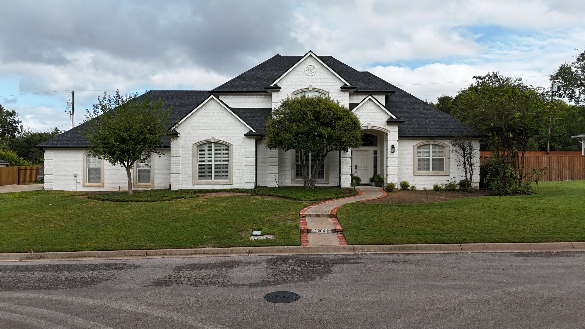 Exterior renovation by Night 'N' Day Construction on a customer's home in Hillsboro, Texas, featuring a new composition shingle roof, freshly painted brick, soffit, fascia, and new gutters.