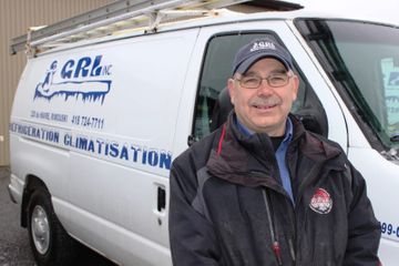 Un homme se tient devant une camionnette de service blanche portant le nom de l'entreprise, « CRL Inc. ».
