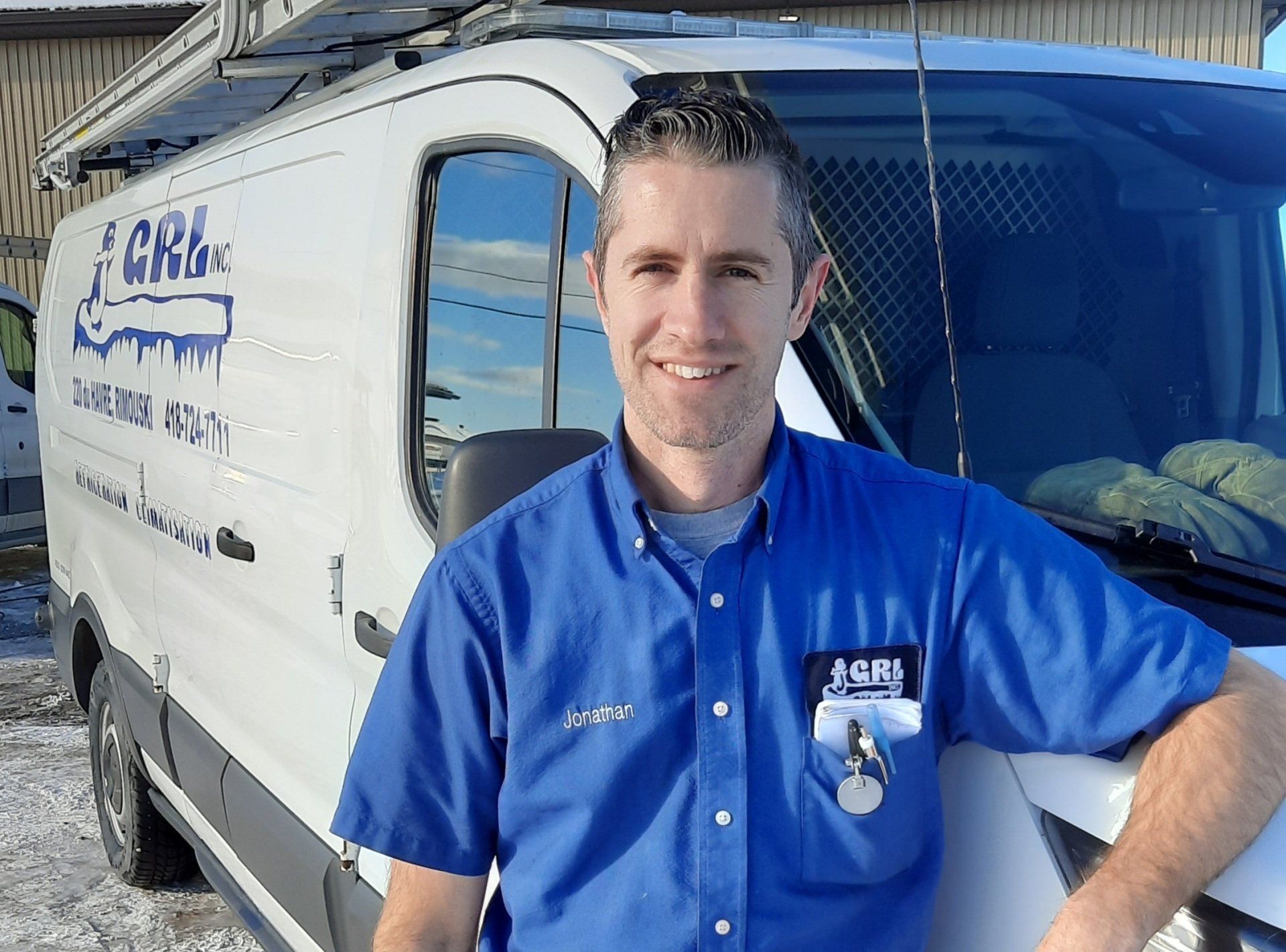 Un homme en chemise bleue s'appuie sur une camionnette blanche portant le logo « CRL Inc. ».