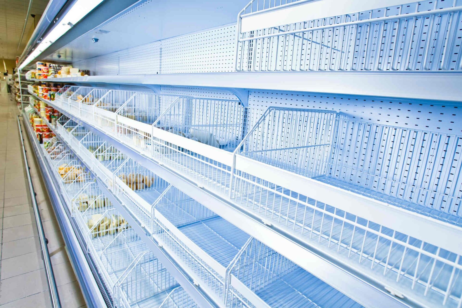 Rayons vides dans un supermarché ; métal blanc, éclairage bleu.