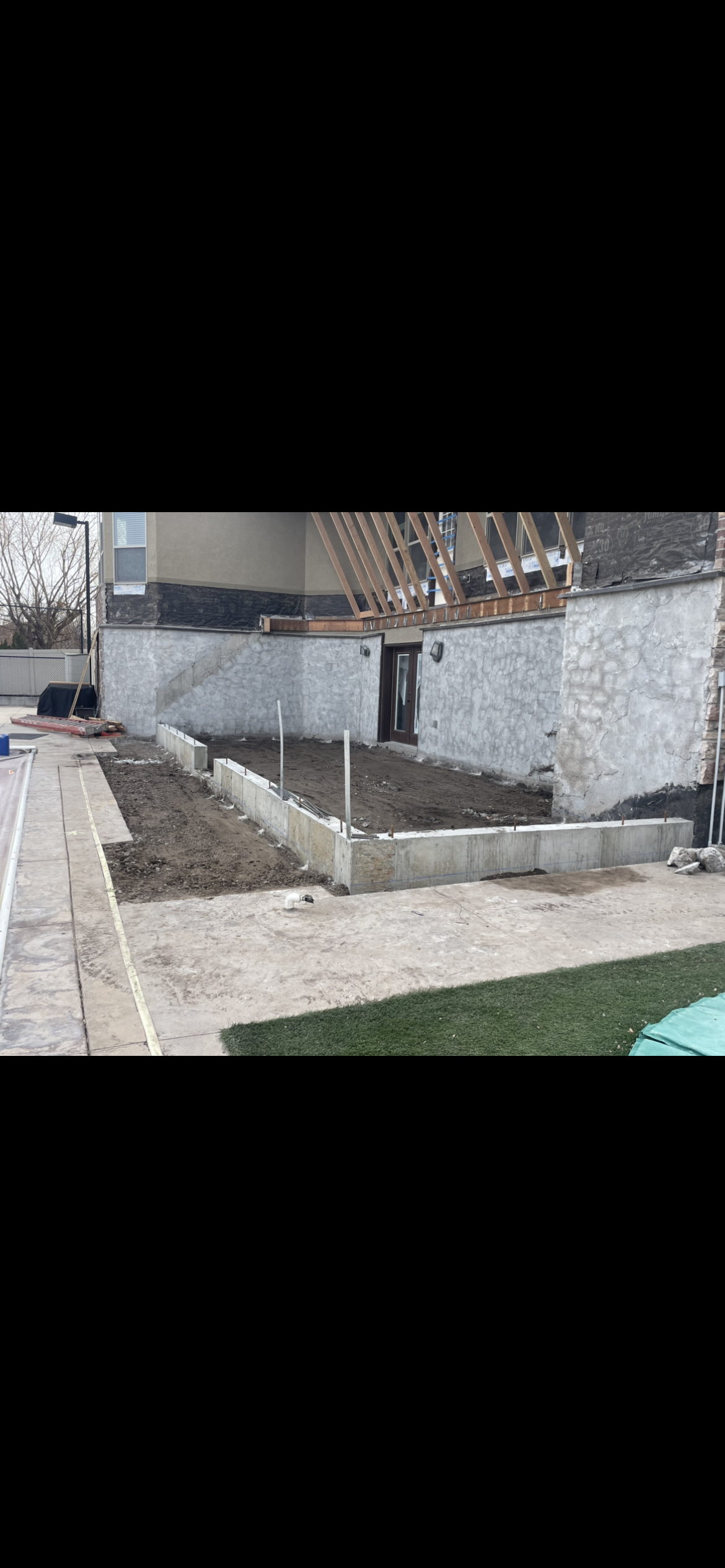 A freshly poured concrete driveway in a suburban neighborhood under a partly cloudy sky.