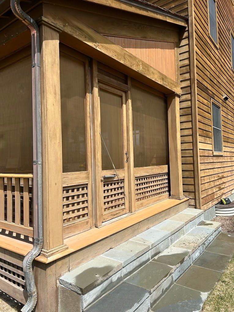 A screened in porch on the side of a house.