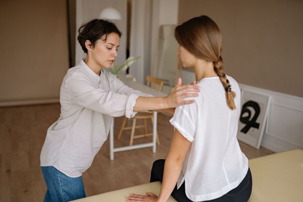 Clinician evaluating a patient with a work-related shoulder and back injury