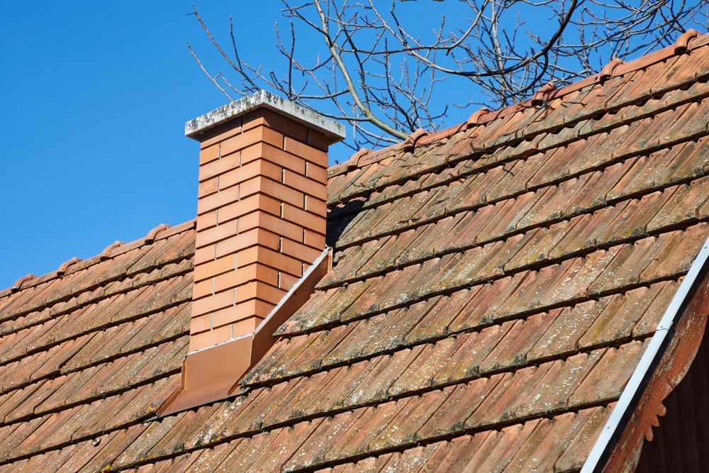 A brick chimney is on the roof of a house.