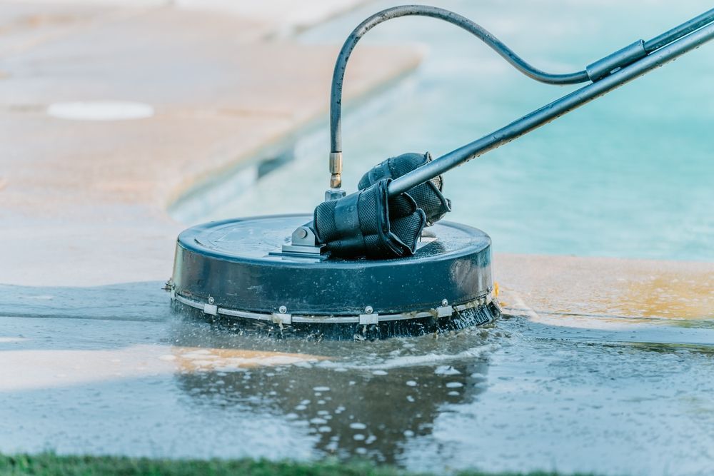 A person is using a pressure washer to clean a concrete surface.