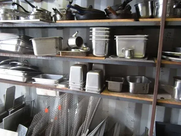 Shelves filled with a variety of stainless steel pots and pans.