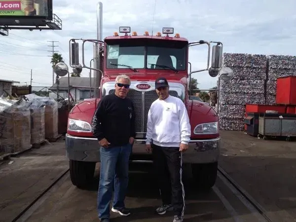 Two men standing in front of a red truck.