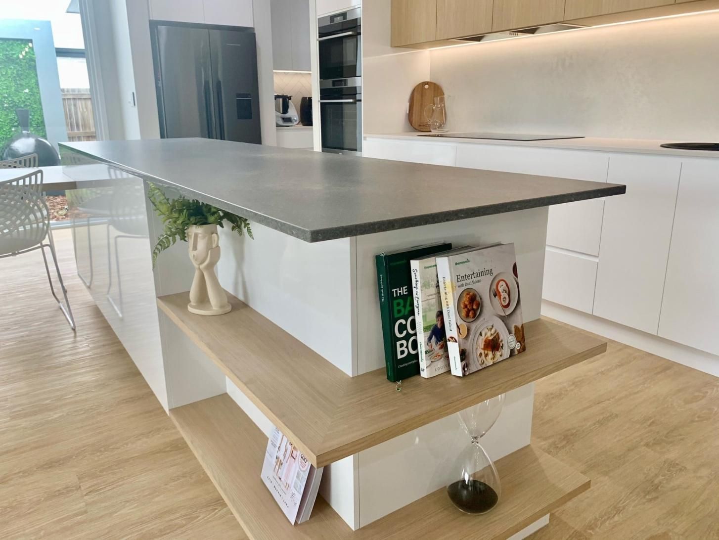 A kitchen with a large island and a shelf with books on it — Olive & White Cabinetmaking in Park Avenue, QLD