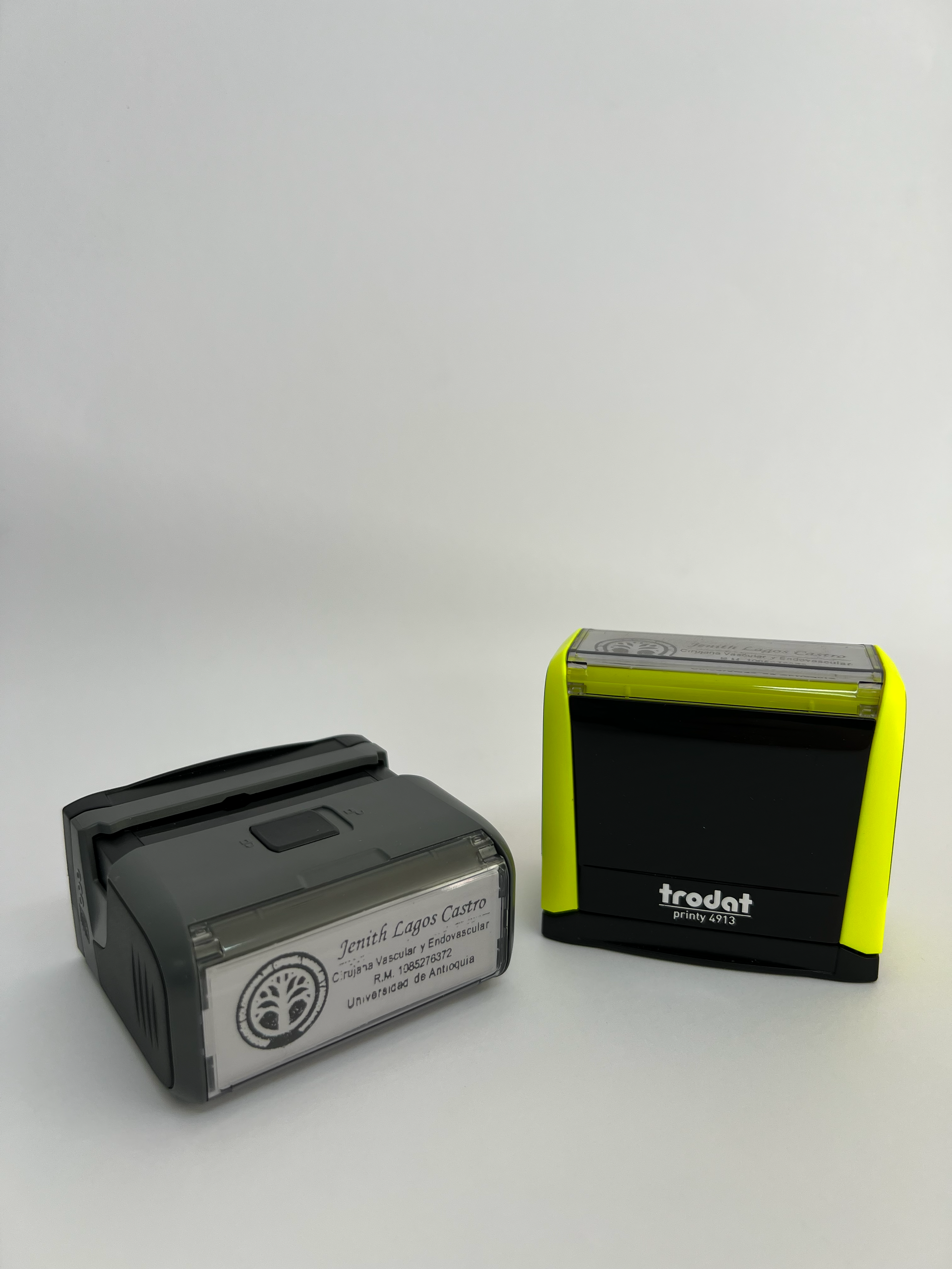 Dos pequeños dispositivos rectangulares sobre una superficie blanca, uno gris y otro negro con bordes de color amarillo neón.