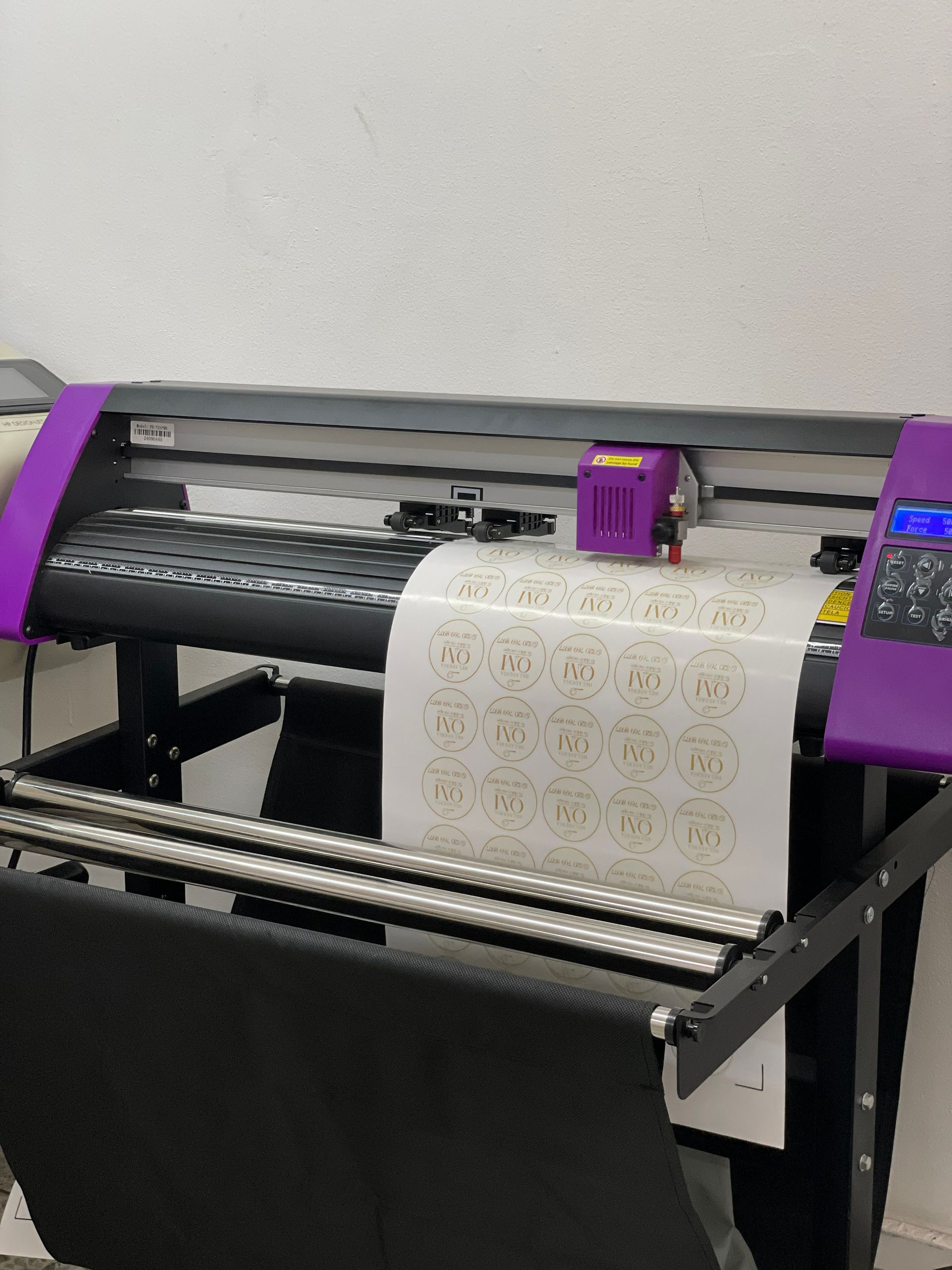 Impresora de gran formato alimentando papel estampado a través de una máquina negra y morada.