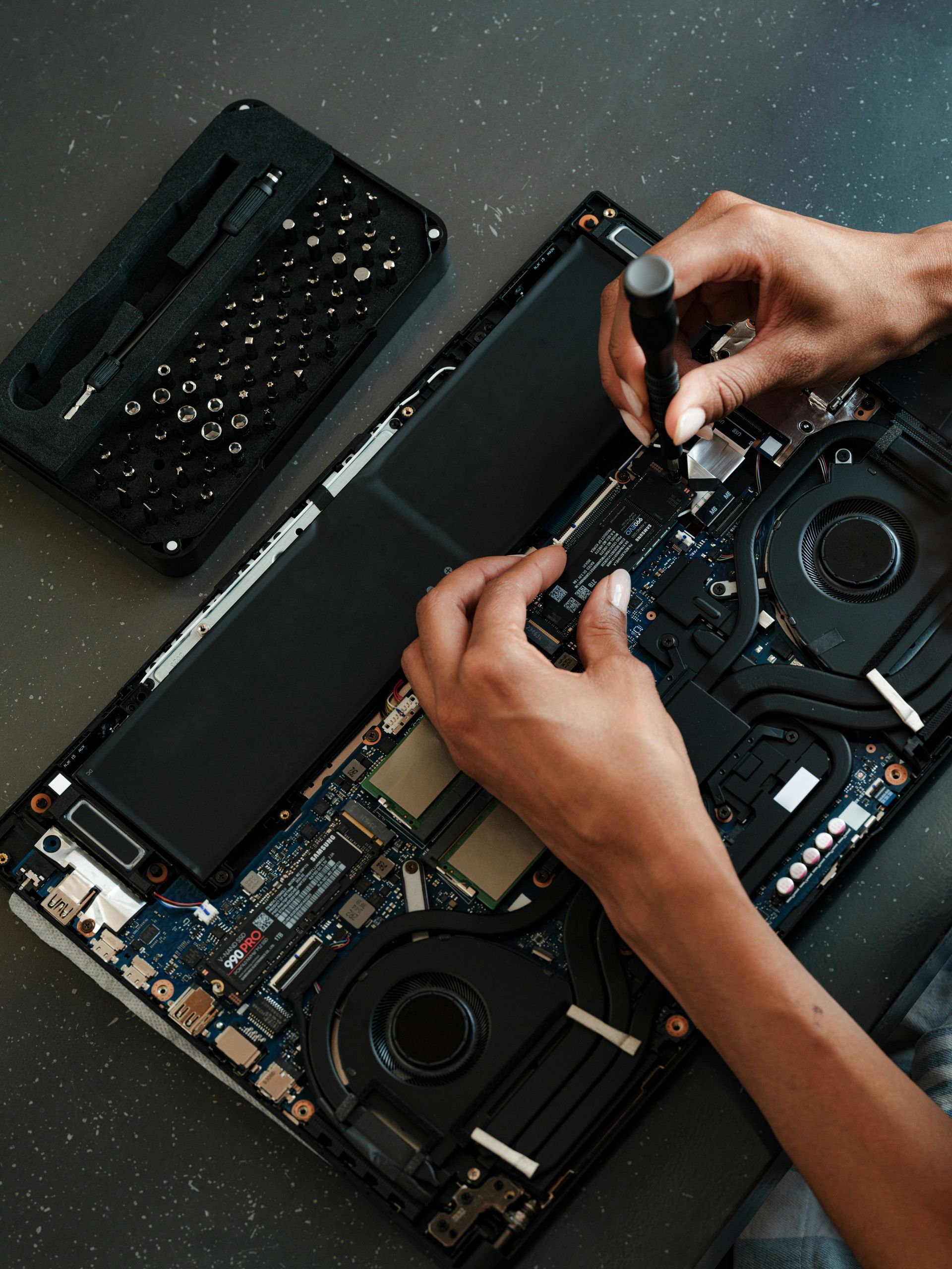 Atikoom technician repairing laptop internals, bottom panel removed, in a Baton Rouge home.
