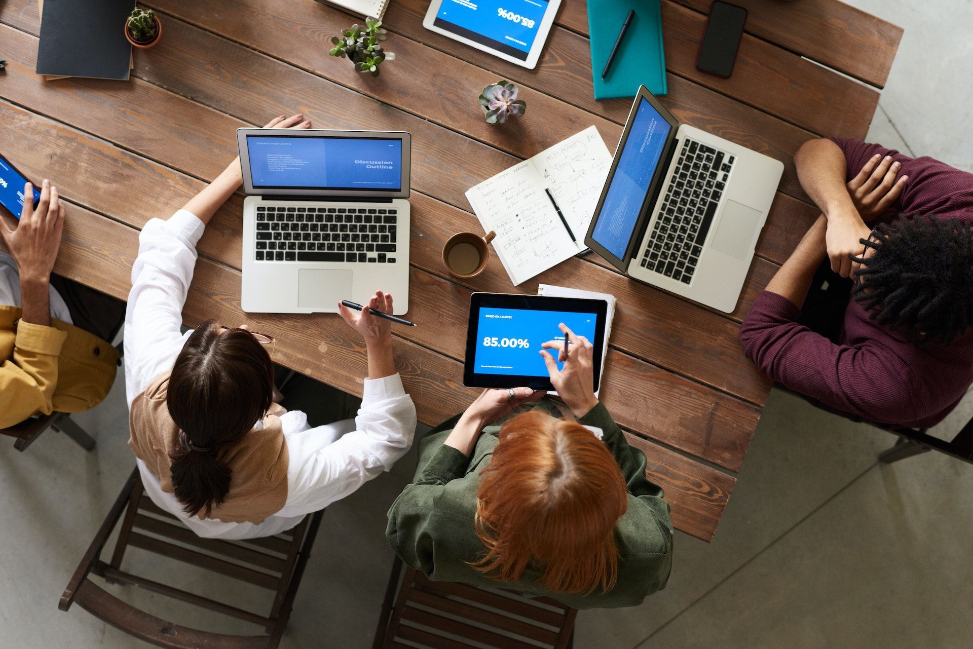 team members in a meeting each with laptops or tablets displaying software being used