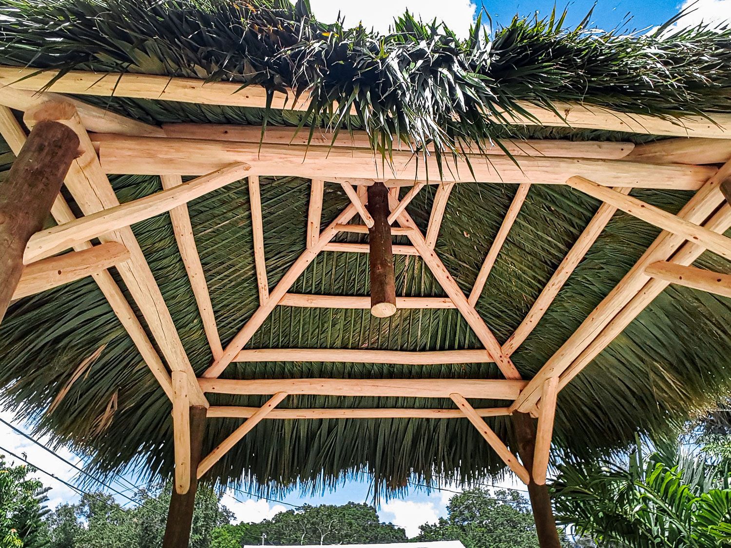 Wooden gazebo with a thatched roof, viewed from below.