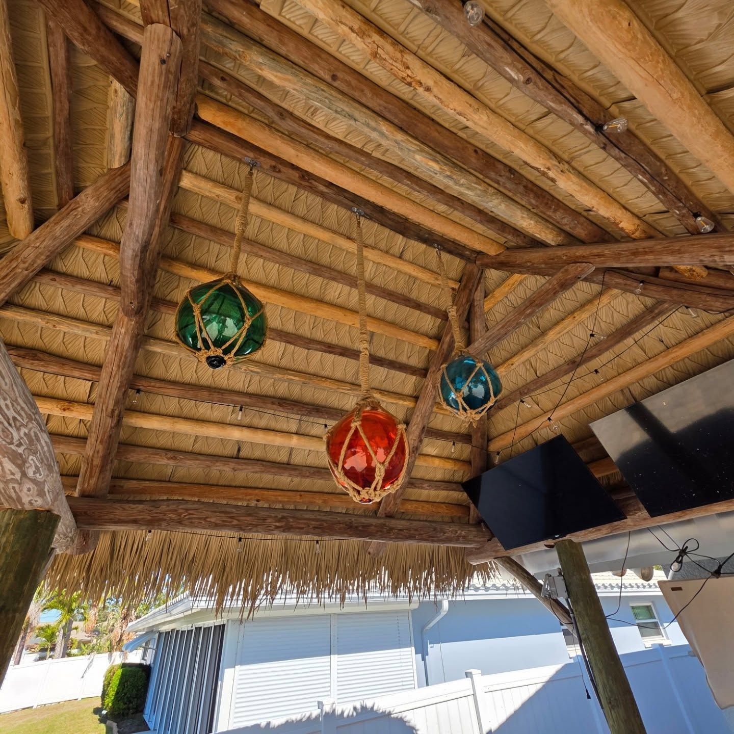 Three colorful hanging glass globes under a thatched roof structure. Three colorful hanging glass globes under a thatched roof structure.