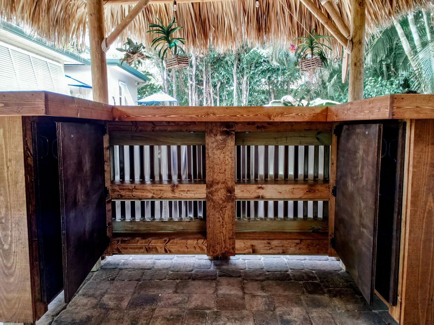 Outdoor bar with wooden frame, thatch roof, and vertical slats.