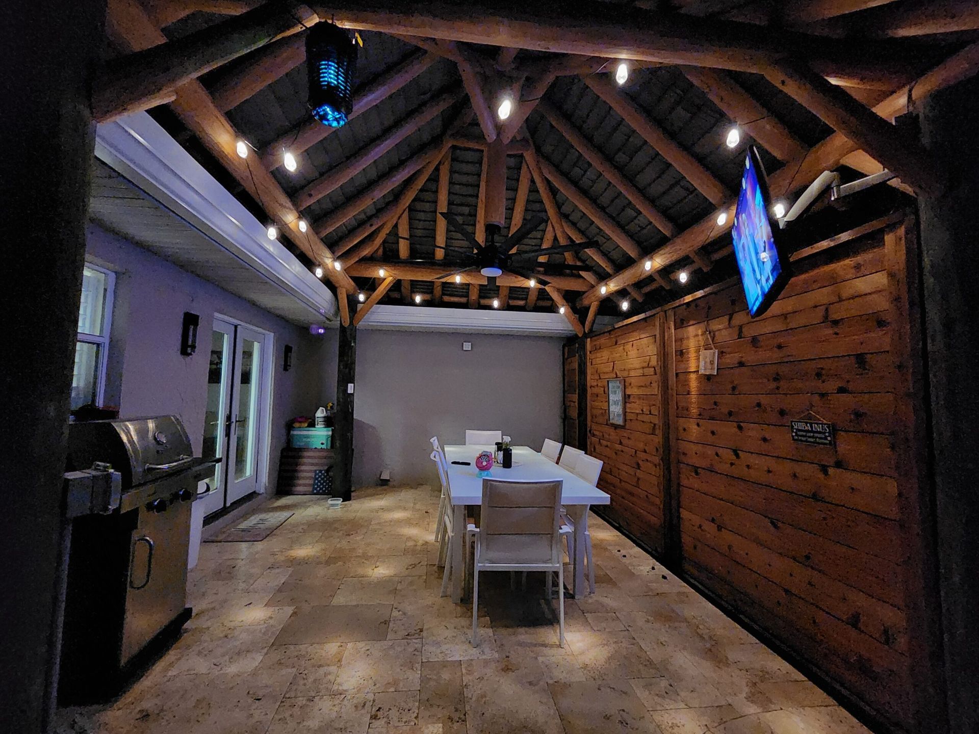 Covered patio with dining set, grill, wooden walls and ceiling, string lights, and TV. Covered patio with dining set, grill, wooden walls and ceiling, string lights, and TV.