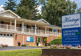 Heritage Monuments funeral home with sign, brick building, and flower bed