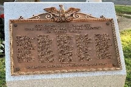 Bronze memorial plaque on a stone base outdoors, with engraved names and an eagle emblem at the top