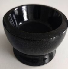 Black ceramic bowl with a pedestal base on a light background