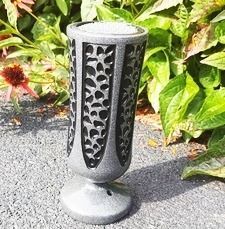 Decorative black metal solar garden light standing on a gravel path by green plants