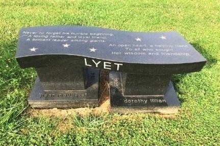 Black memorial bench tombstone on grass engraved with stars and the word “LYET”