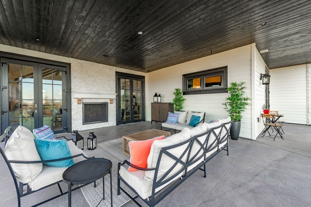 Patio with seating, fireplace, and black accents under a black ceiling.