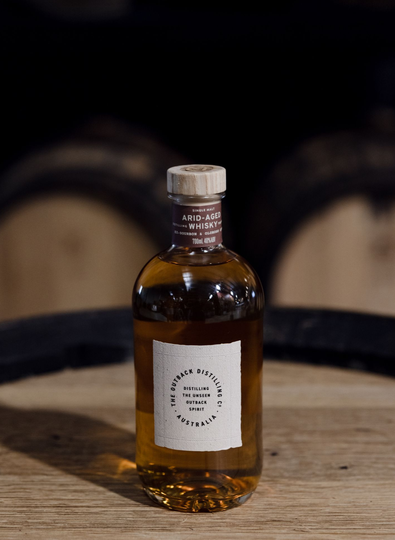 Australian Native Dry Gin by The Outback Distilling Co on barrel in distillery setting.