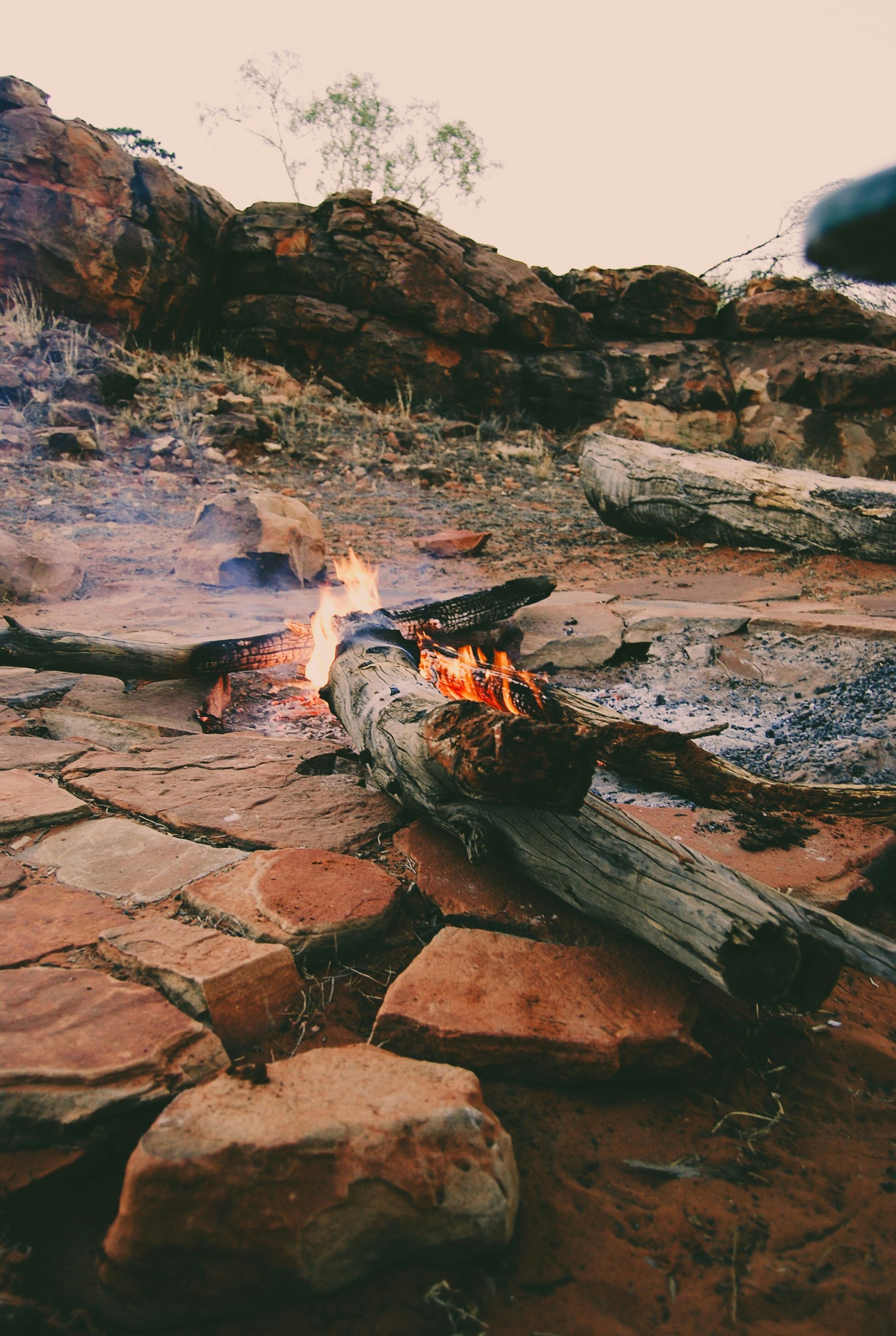 campfire burning among red rocks in an Australian Outback landscape