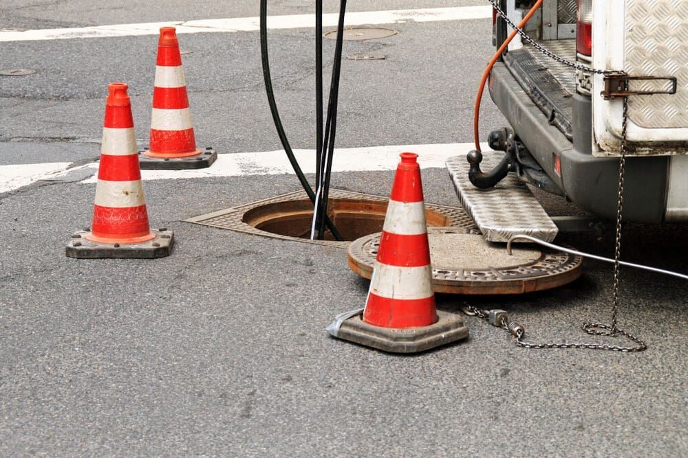 A Group of Traffic Cones Are Sitting Next to a Manhole Cover — Tailored Spatial Solutions in Cairns City, QLD