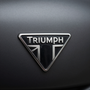 Close-up of a silver Triumph motorcycle emblem on a matte black surface