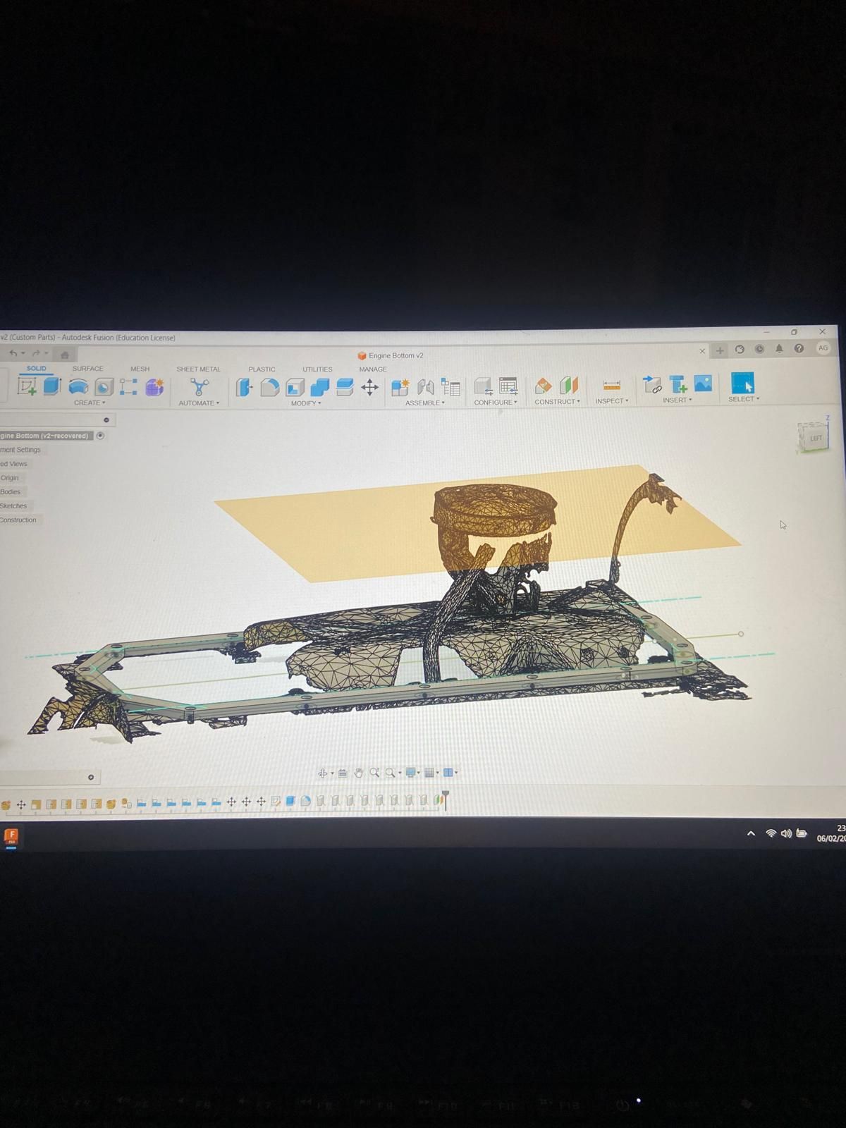 CAD software showing a 3D model of a mechanical assembly with a cylindrical part and frame on a computer screen