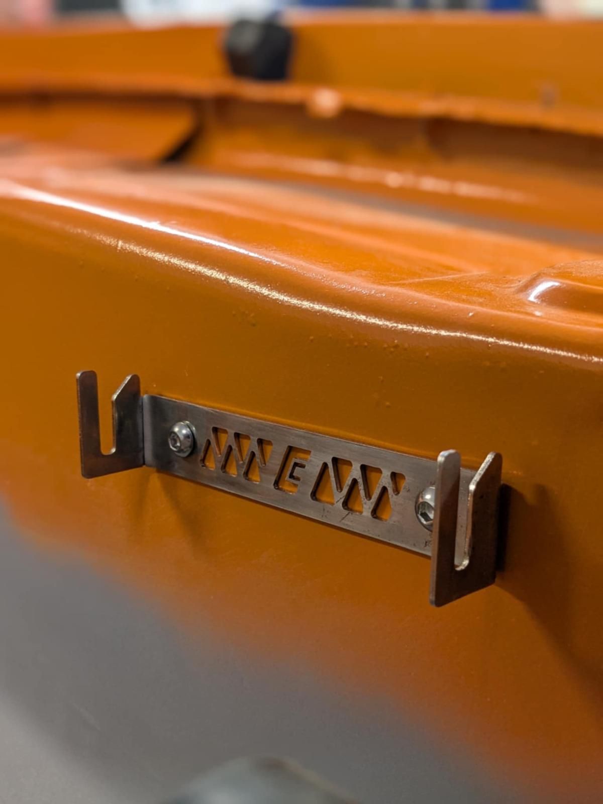 Close-up of an orange metal surface with a small black and silver latch or bracket.