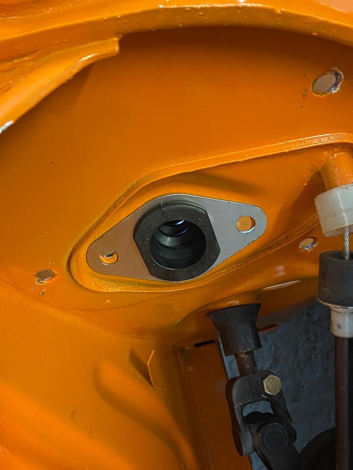 Close-up of orange machine panel with a mounted camera lens and metal fasteners.