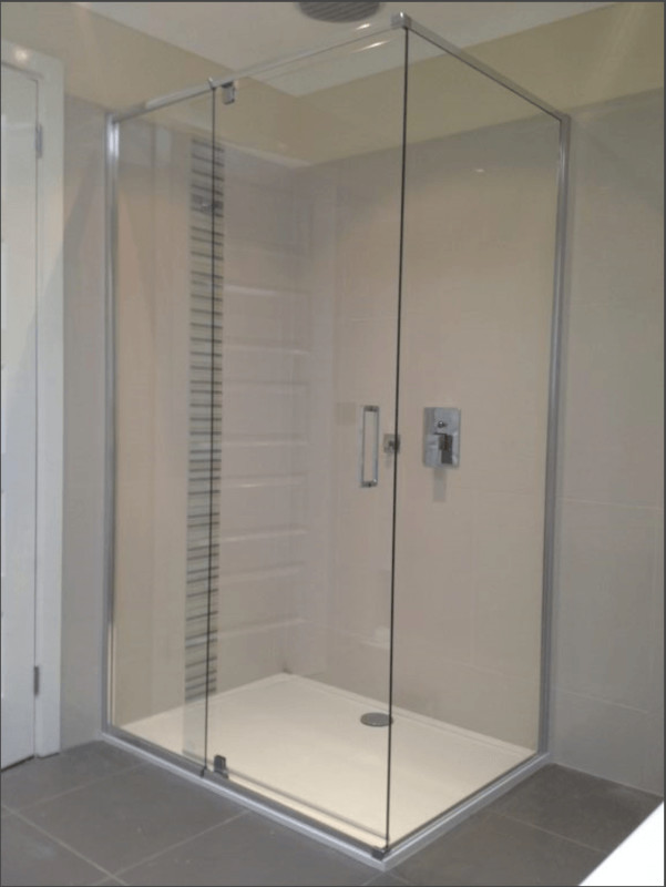 Glass shower enclosure in a bathroom with a white base and neutral walls.
