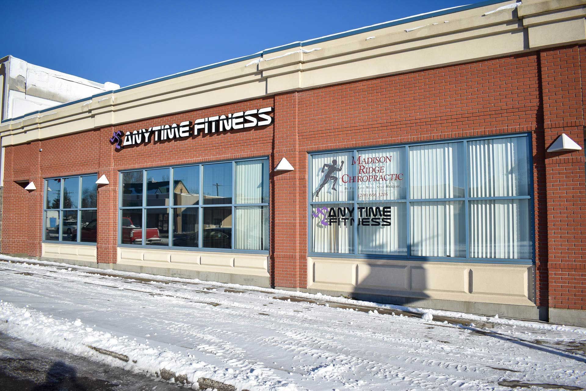Snowy storefront of Anytime Fitness with brick exterior and large windows