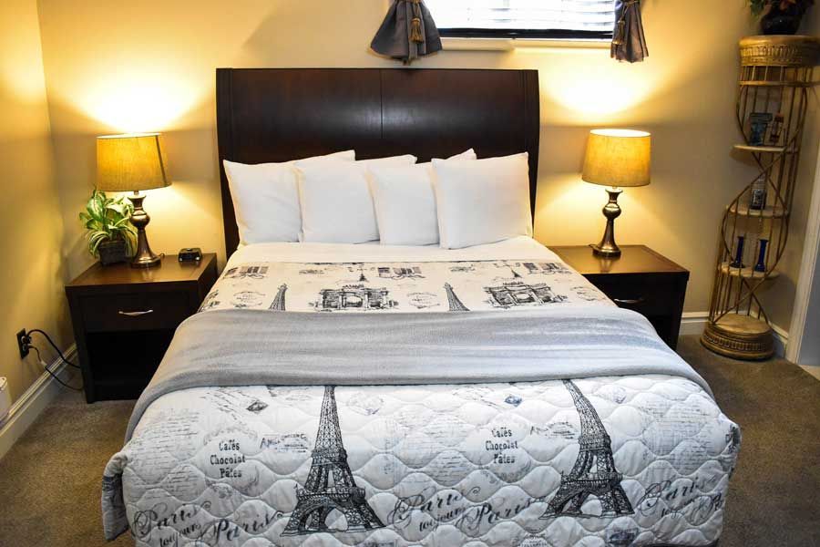 Cozy bedroom with a made bed, white pillows, bedside lamps, and dark wood furniture