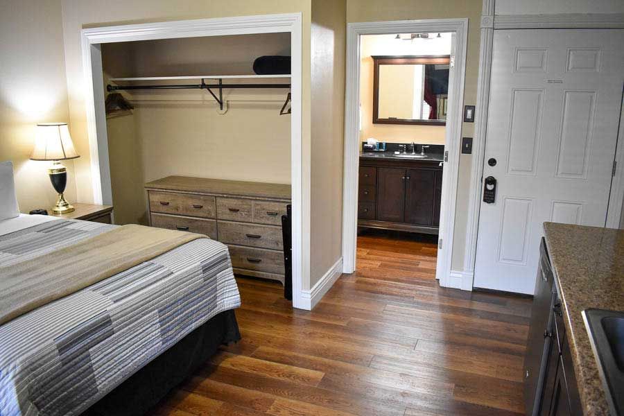 Bedroom with king bed, closet, dresser, and an open door to a bathroom, in warm neutral tones.