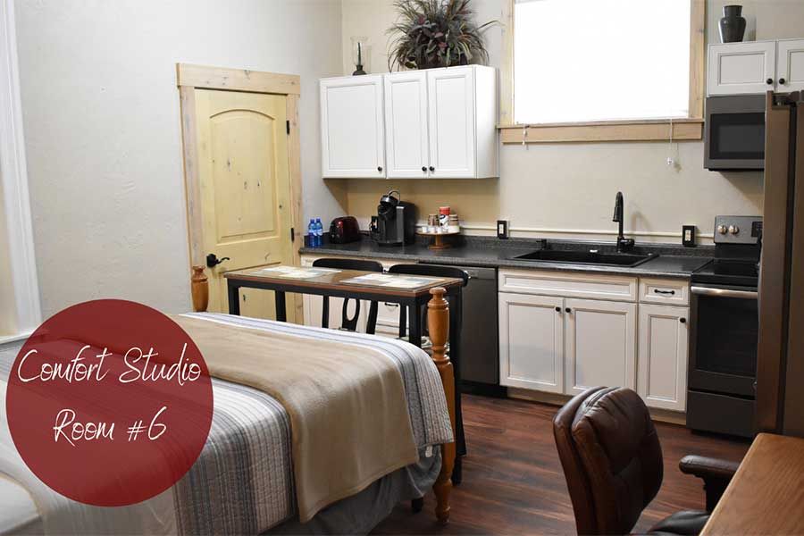 Studio apartment bedroom and kitchen with bed, cabinets, and wooden door