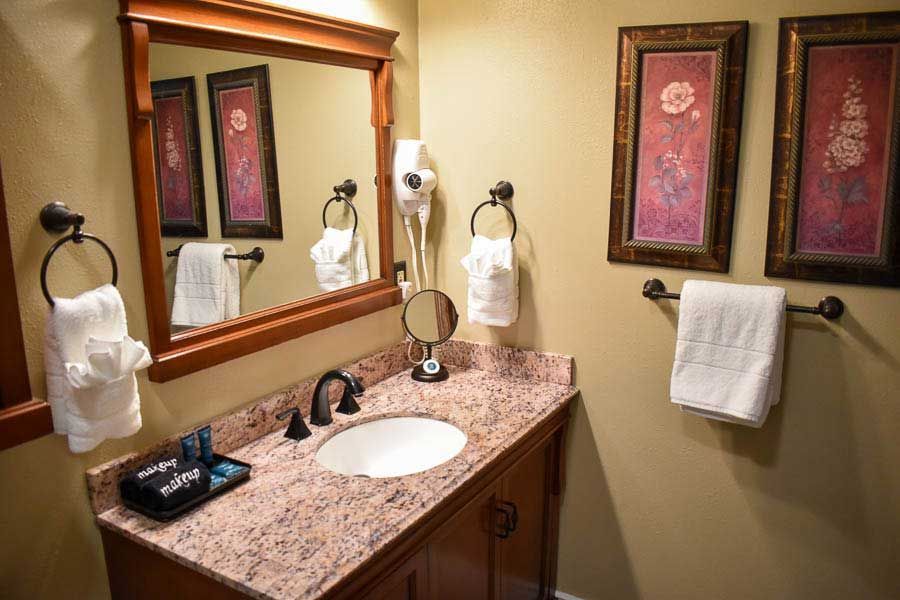 Bathroom vanity with granite countertop, sink, mirror, towels, and decorative wall art.