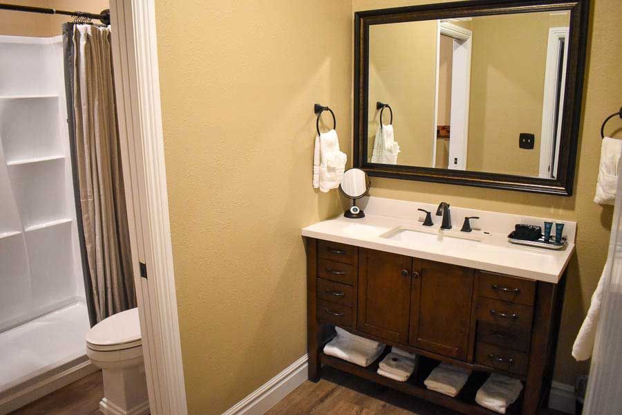 Bathroom with vanity, mirror, sink, toilet, shower curtain, and beige walls