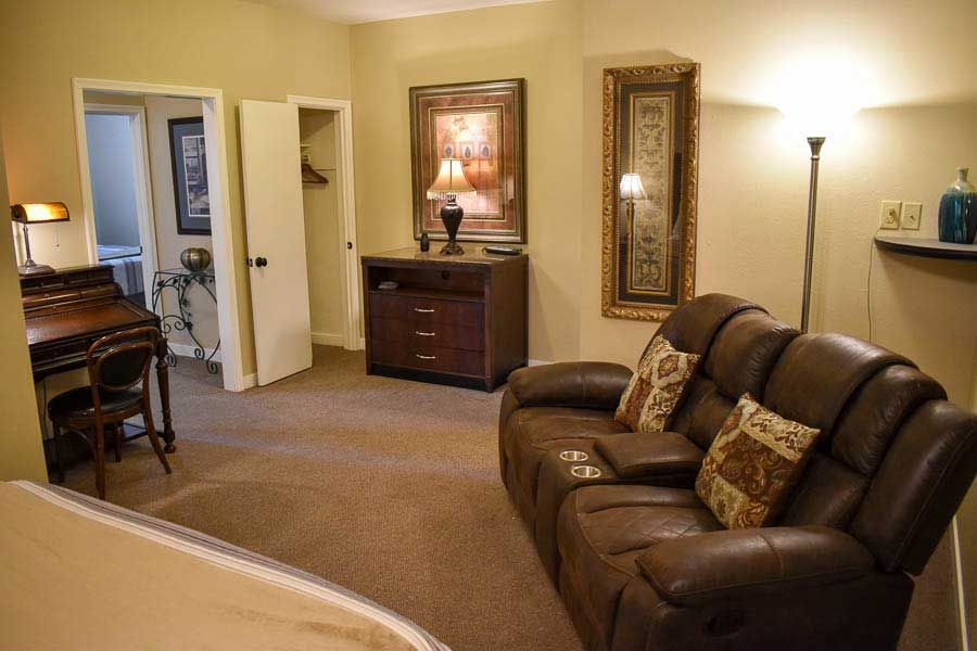 Living room with brown leather sofa, lamp, and cabinet in a warmly lit apartment