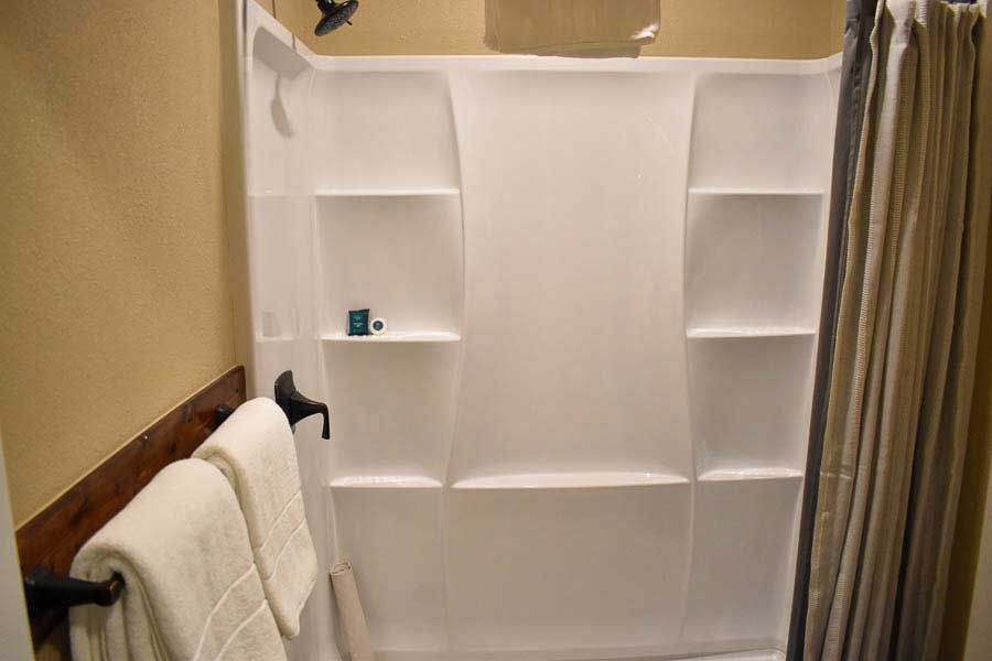 Bathroom shower with built-in white shelves and a towel hanging nearby