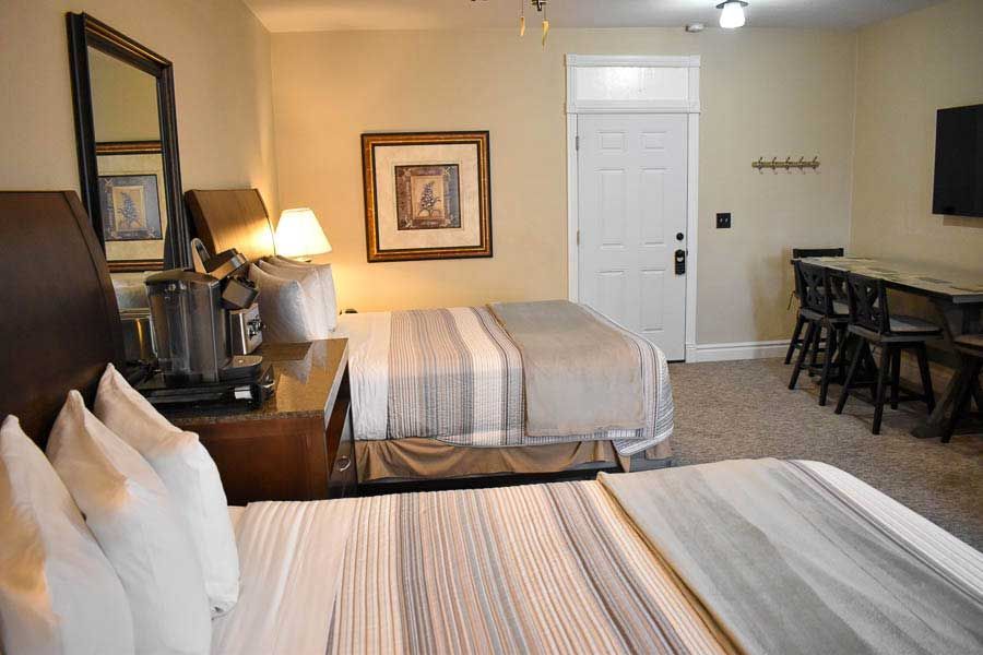 Hotel room with two beds, dresser, wall art, and a small desk area