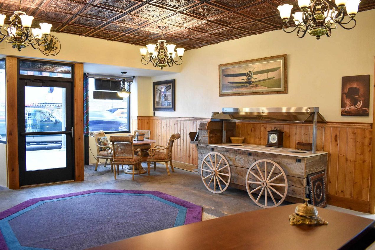 Cozy vintage lobby with woven ceiling, chandeliers, wooden furniture, and wagon-wheel decor