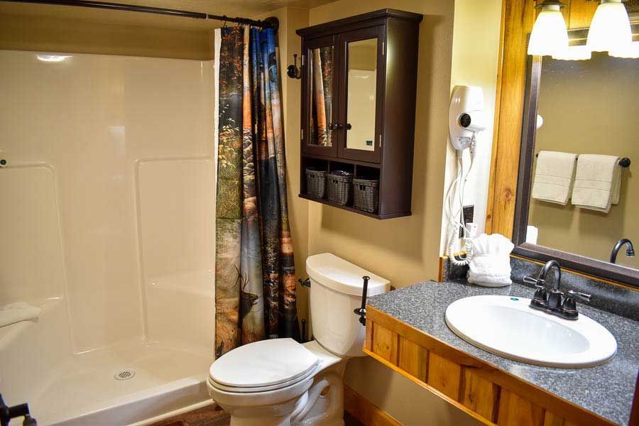 Bathroom with shower-tub, toilet, vanity sink, mirror, and warm yellow walls