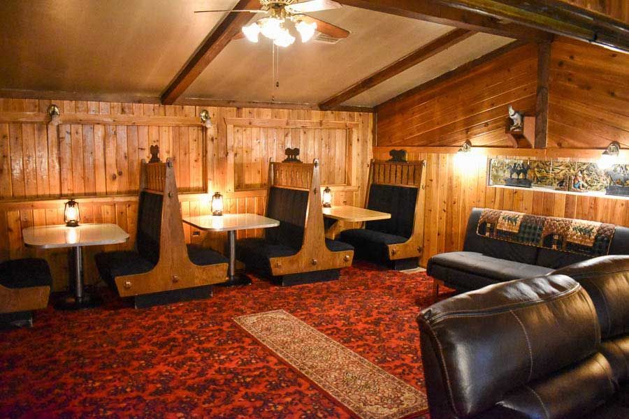 Wood-paneled lounge with booths, tables, warm lighting, and red patterned carpet