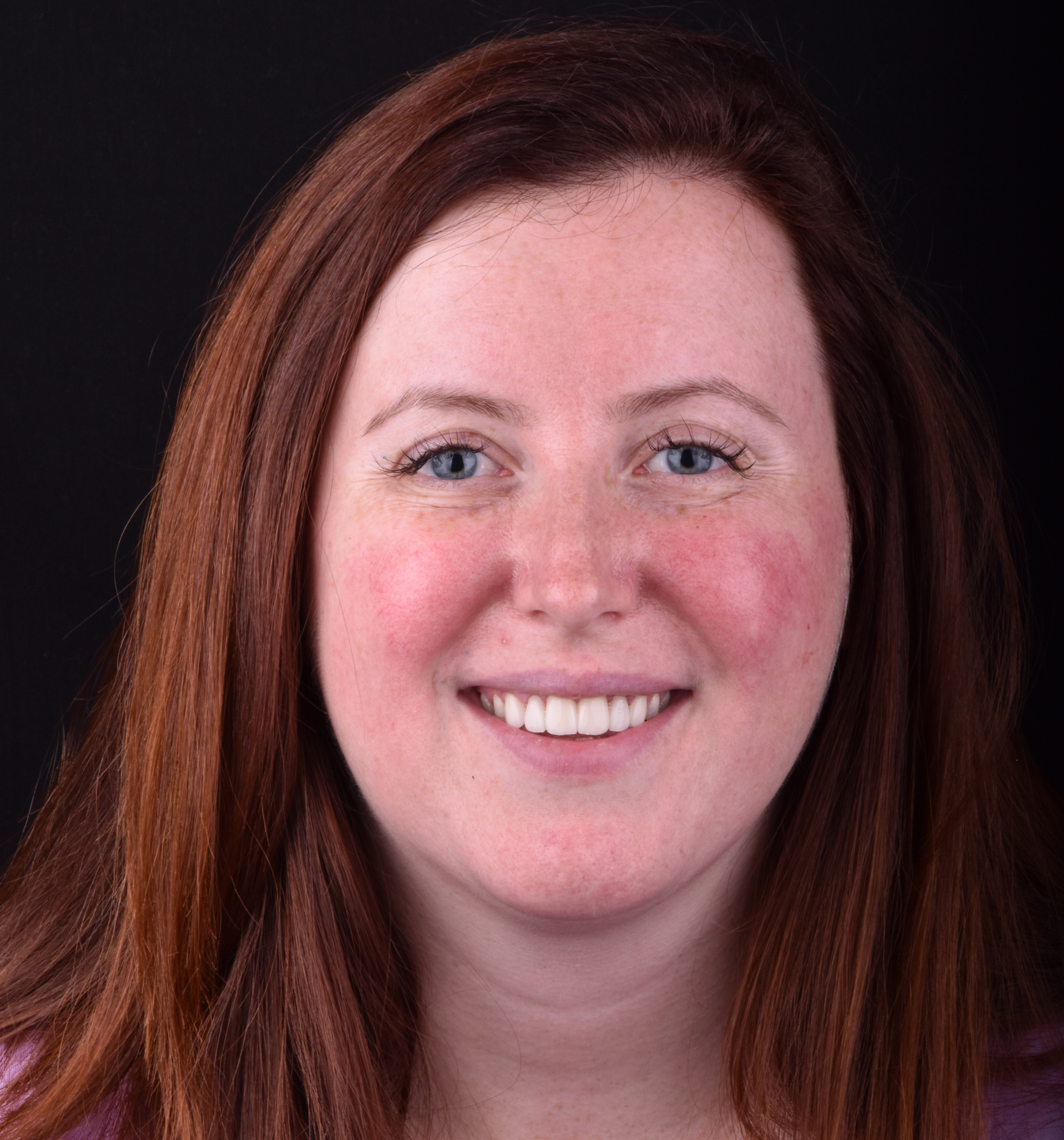 Smiling woman with auburn hair on a dark background
