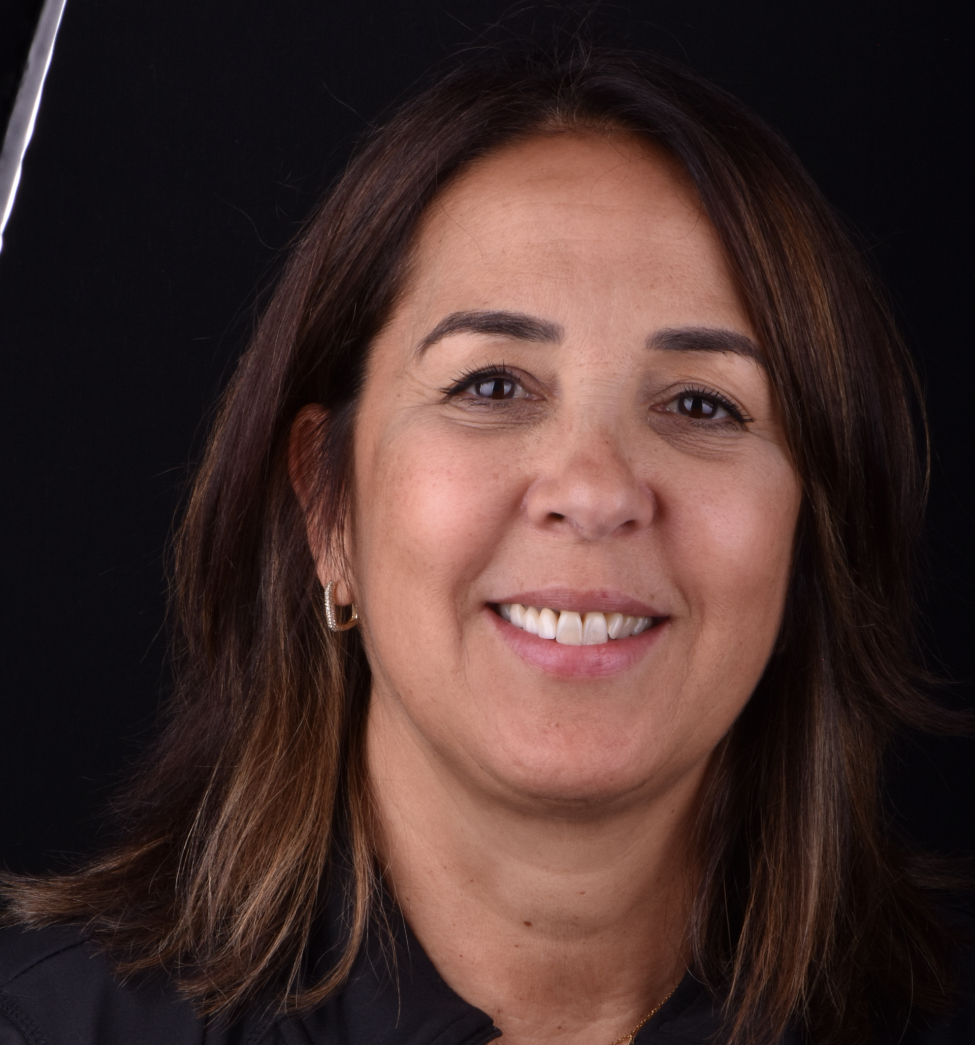 Smiling woman with shoulder-length brown hair against a dark background